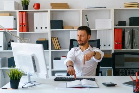 Young beautiful man work on computer sit at table in office smile Stock Photos