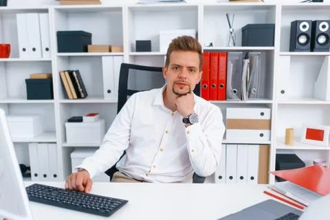 Young beautiful man work on computer sit at table in office smile Stock Photos
