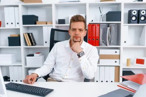 Young beautiful man work on computer sit at table in office smile Stock Photos
