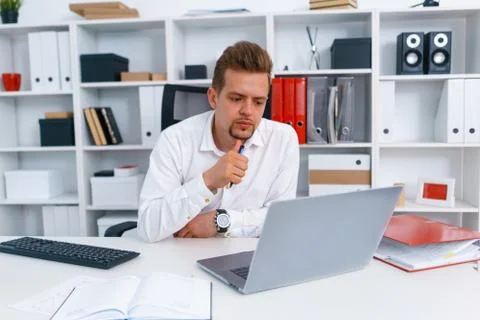 Young beautiful man work on computer sit at table in office smile Stock Photos