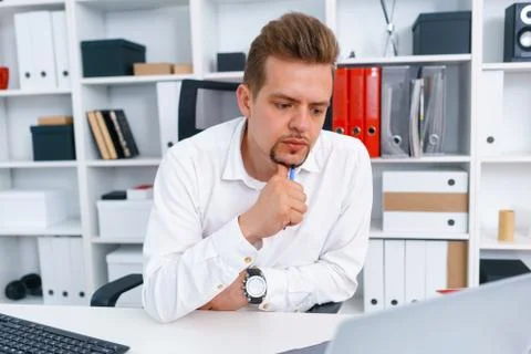 Young beautiful man work on computer sit at table in office smile Stock Photos