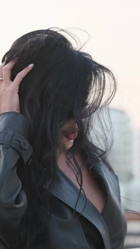 A young beautiful model with long black hair with good makeup fixes her hair. Stock Footage 332097612