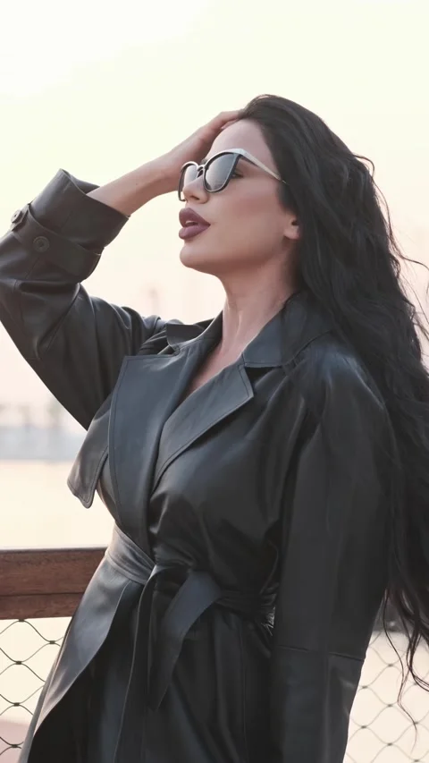 A young beautiful model with long black hair with good makeup fixes her hair. Stock Footage 332100257