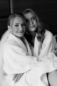 Young beautiful models sit on the bed in white coats. Black and white photo Stock Photos