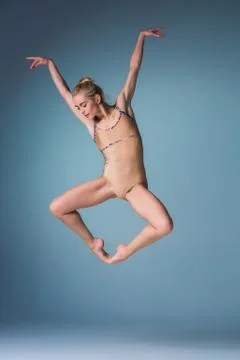 Young beautiful modern style dancer jumping on a studio background Stock Photos