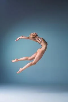 Young beautiful modern style dancer jumping on a studio background Stock Photos