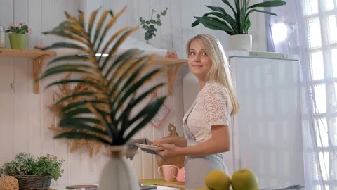 Young beautiful mom prepares dinner in the kitchen for her family and smiles Stock Footage 128584093