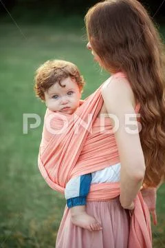Young beautiful mother hugging her little toddler son against green grass. Happy Stock Photos