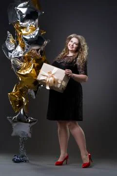 Young beautiful plus size model in black dres with gift box Stock Photos