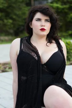 Young beautiful plus size model professional makeup sitting outdoors Foto stock