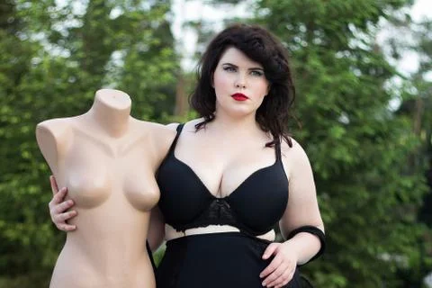 Young beautiful plus size modelt in black bra holding mannequin Stock Photos
