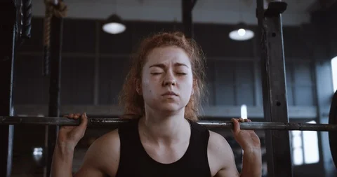 Young beautiful red haired athletic woman straining hard lifting heavy barbell Stock Footage 116874810