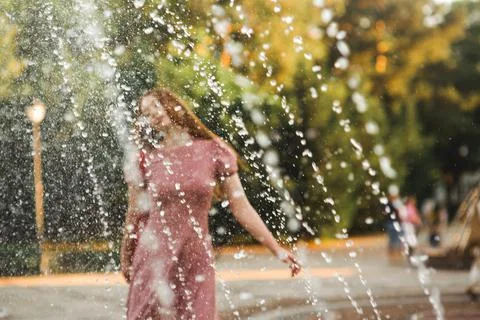 Young beautiful red-haired long-haired woman in a summer pink dress walks Foto stock