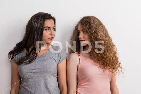 Young beautiful serious women in studio, looking at each other. Stock Photos