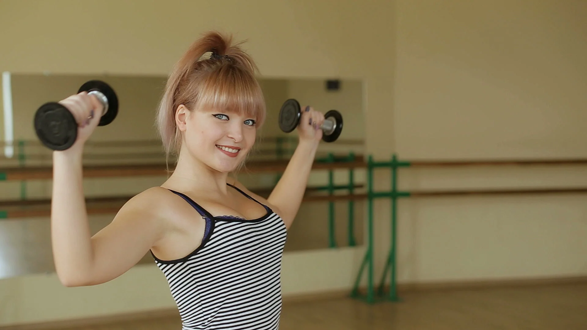 Young beautiful sexy girl working out with dumbbells in gym.