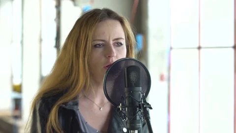 Young beautiful singer singing into the microphone at the studio Stock Footage 73718915