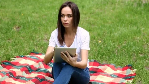 The young beautiful slim dark-haired woman working on the tablet in a park. HD 库存影片 76085535