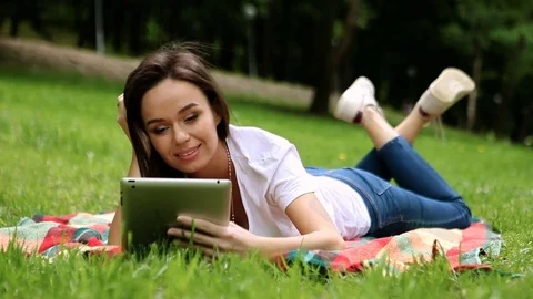 The young beautiful slim dark-haired woman working on the tablet in a park. HD Stock Footage 76085608