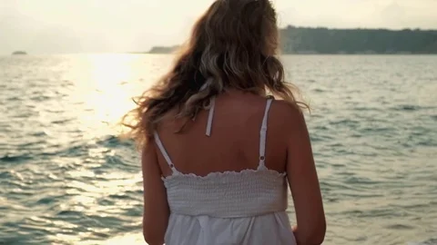 Young beautiful smiling girl walking on a beach at sunset Stock Footage