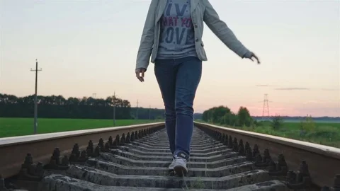 Young beautiful trendy woman walking on railroad track. Stock Footage