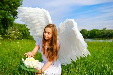 Young beautiful white girl with angel wings plays with waterlily Stock Photos