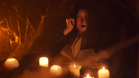 Young beautiful witch in a black robe looking at the camera. Halloween horror 스톡 동영상 163389541
