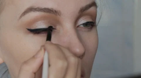 Young beautiful woman applying eyeliner with brush Stock Footage