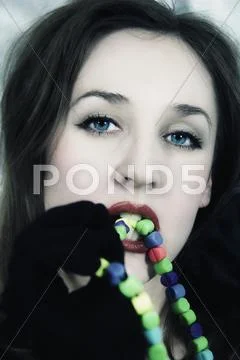 Young beautiful woman biting multi-coloured beads Stock Photos