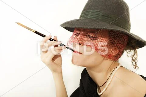 Young beautiful woman with cigarette in mouthpiece in hat with veil Stock Photos