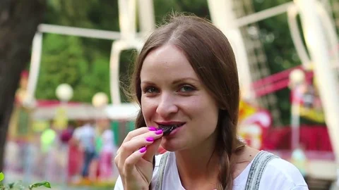 Young beautiful woman eating oreo cookies in the amusement park. Stock Footage