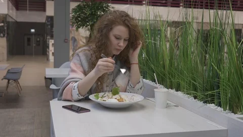 Young beautiful woman eats caesar salad in a cafe Stock Footage 102347323