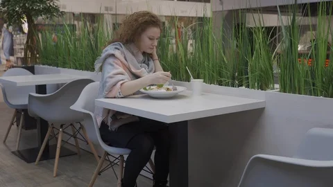 Young beautiful woman eats caesar salad in a cafe Stock Footage 102347728