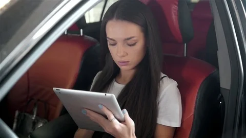 Young, beautiful woman fastens a seat belt, sitting in the back seat of the car Stock Footage