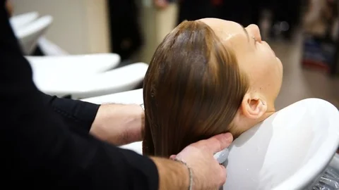 A young beautiful woman getting her hair washed at hairdressers, 4K Stock Footage