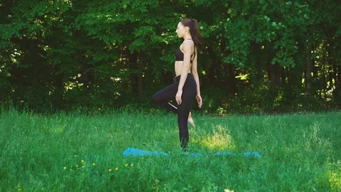 Young beautiful woman practicing outdoors, doing posture Stock Footage