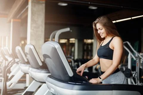 Young beautiful woman programming a threadmill to make her morning jog even Stock Photos