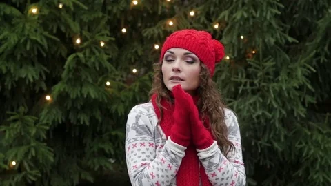 Young beautiful woman in a red cap scarf and mittens basks on a background of Stock-Footage 80885341