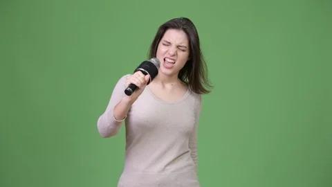 Young beautiful woman singing against green background Stock Footage