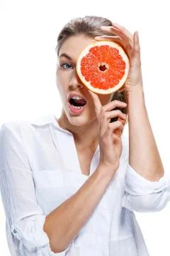 Young beautiful woman with the slice of grapefruit in front of her eye isolated Stock Photos