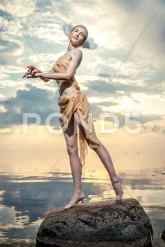 Young beautiful woman as swan posing on the beach at sunset Stock Photos