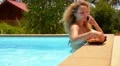 Young Beautiful Woman Talking on Cell Phone and Eating Pineapple in Pool. HD Footage