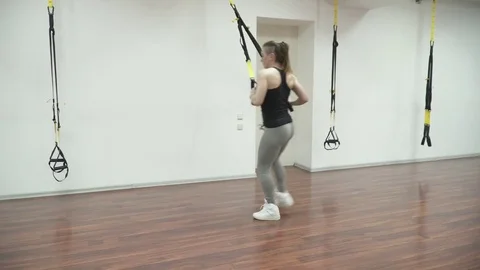 Young beautiful woman training trx in the fitness hall Stock Footage