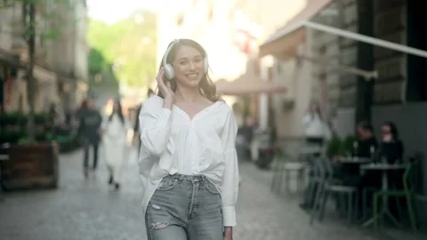 Young beautiful woman using mobile phone in the city while listening music Stock Footage 198017612