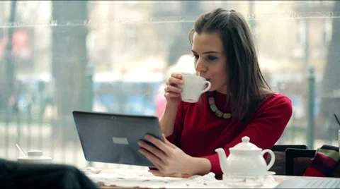 Young, beautiful woman using tablet and drinking tea in the cafe Vídeo Stock 36645455