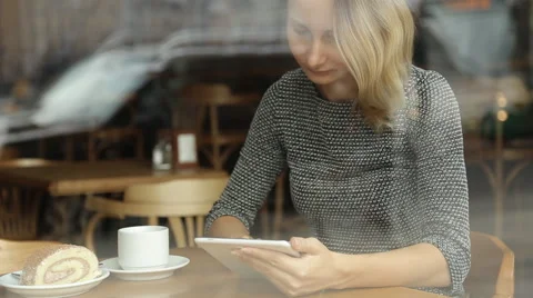 Young, beautiful woman using tablet and drinking tea in the cafe Stock Footage 67512828