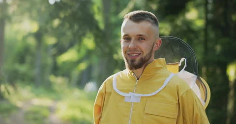 A young bee keeper working in the woods by the apiary hives stands with the bite 스톡 동영상 165005284