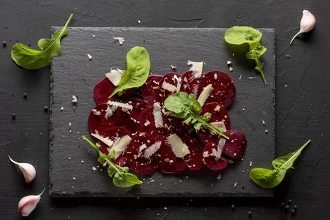 Young beet carpaccio with parmesan, nuts, arugula and garlic with olive oil.  Stock Photos