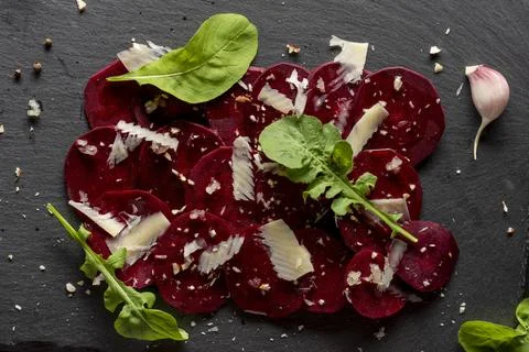 Young beet carpaccio with parmesan, nuts, arugula and garlic with olive oil.  Stock Photos
