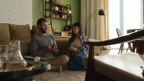Young beloved couple sit on floor near couch chatting at home Video stock 266801433