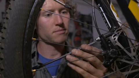 A young bicycle mechanic working on a mountain bike - dolly shot Stock Footage 69907375
